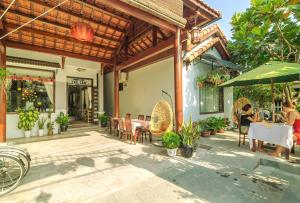 a patio with a table and chairs and an umbrella at Tue Tam Garden Villa in Hoi An