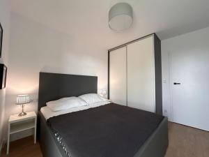 a bedroom with a large bed with a black headboard at Posesja Kapitańska Apartament 18B 17 przy plaży in Grzybowo