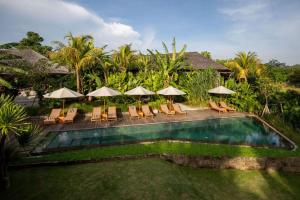 a pool with chairs and umbrellas in a resort at Sejati Boutique Hotel Uluwatu in Uluwatu