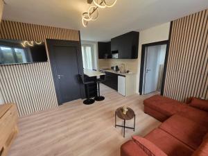 a living room with a red couch and a kitchen at L'aulne in Carhaix-Plouguer