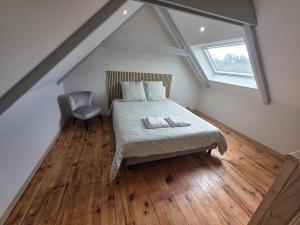 a attic bedroom with a bed and a window at L'aulne in Carhaix-Plouguer