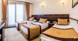ein Hotelzimmer mit drei Betten und einem Fenster in der Unterkunft Grandwork Hotel in Dikmen