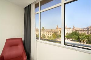 a red chair sitting in a room with a large window at Hotel Pasarela in Seville