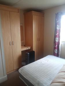 a bedroom with a bed and wooden cabinets and a window at Arizona Caravan in Camber