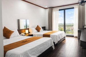 a hotel room with two beds and a balcony at Tiến Thành Hotel Nghệ An in Vinh