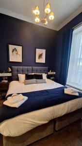 a bedroom with a large bed with blue walls at The Clock Face Prescot in Prescot