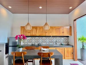 a kitchen with wooden cabinets and a table with chairs at Moonlight Heaven Villa Ubud 2BR Private Pool in Tampaksiring
