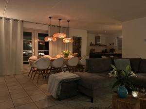 a living room with a couch and a table with chairs at Duinvilla met sauna en whirlpool in Makkum
