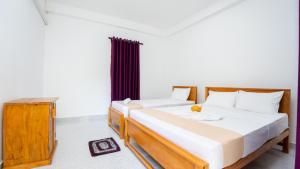 a bedroom with two beds and a table at Near Town Lodge in Dambulla