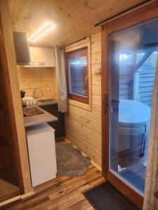 a small kitchen in a log cabin with a glass door at Pici vendégház in Noszvaj