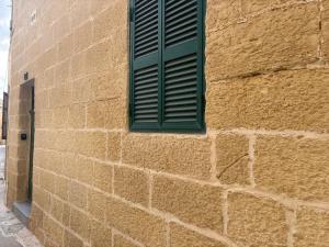 a green window on the side of a brick building at Guesthouse 39 in Mqabba