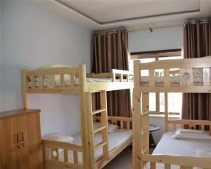 a room with three bunk beds and a window at The Silk Road Travelers Hostel in Zhangye