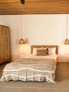 a bedroom with a bed and two pendant lights at La La Villas in Pulau Pototogat