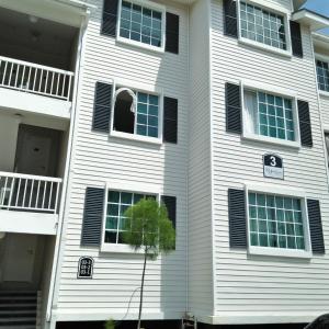 a white house with black shuttered windows and a tree at MZ Homestay Kampar in Kampar