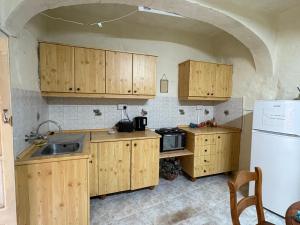 a kitchen with wooden cabinets and a sink and a refrigerator at Guesthouse 39 in Mqabba