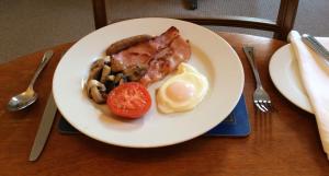 a plate of food with eggs bacon and a tomato at The Old Post House in Moretonhampstead