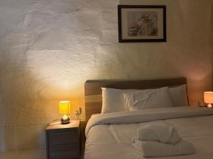 a bedroom with a white bed with a night stand with a lamp at Guesthouse 39 in Mqabba
