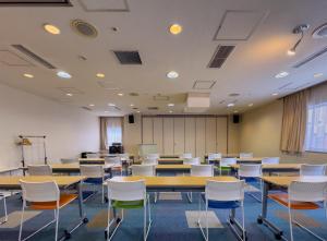 an empty room with tables and chairs in a classroom at Court Hotel Asahikawa in Asahikawa