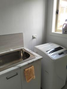 a kitchen with a sink and a washing machine at Comfort and good value in Melton South