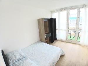 a white bedroom with a bed and a window at Eves Rooms in Saint-Michel-sur-Orge