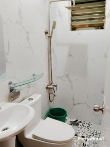 a white bathroom with a toilet and a sink at Zoldyck 2 Home in Pahanocoy
