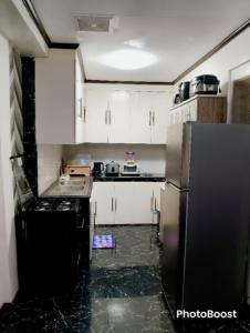 a kitchen with white cabinets and a black refrigerator at Zoldyck 2 Home in Pahanocoy