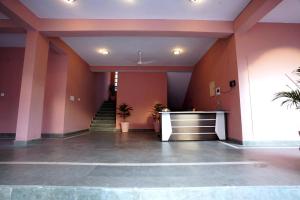a lobby with pink walls and a staircase at Gangabagh by Divine Trails - Hotel Near Har Ki Pauri, Haridwar in Haridwār