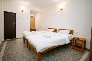 two beds in a room with white sheets at Gangabagh by Divine Trails - Hotel Near Har Ki Pauri, Haridwar in Haridwār +23 photos
