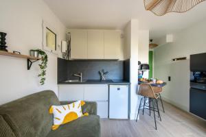 a living room with a couch and a kitchen at Jardin du Golf wifi Clim in La Grande Motte
