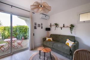 a living room with a green couch and a table at Jardin du Golf wifi Clim in La Grande Motte
