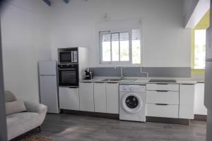 a kitchen with white cabinets and a washer and dryer at La kaz a sonel, gîte au vert in Morne-à-lʼEau