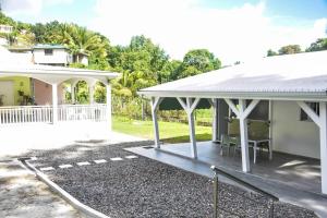 a white house with a porch and a patio at La kaz a sonel, gîte au vert in Morne-à-lʼEau