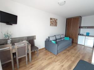 a living room with a table and a couch and a kitchen at Villa Over Lake in Mielno