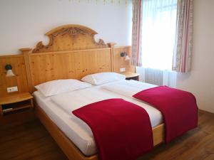a bedroom with a large bed with a wooden headboard at Landhotel Postgut - Tradition seit 1549 in Tweng