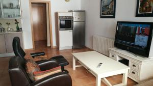 ein Wohnzimmer mit Fernseher, Sessel und Tisch in der Unterkunft Carudo in Llafranc