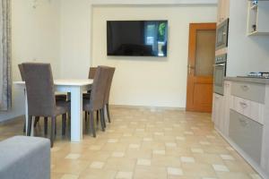 a kitchen with a table with chairs and a television on the wall at Casa Solemare Strongoli in Marina di Strongoli +18 photos