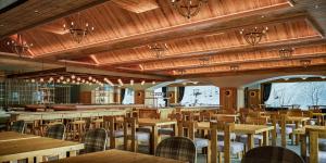 an empty restaurant with wooden tables and chairs at The Alps Hotel Hakuba in Otari