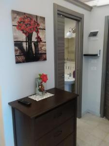 baño con tocador de madera con flores rojas en Cusmano Residence, en Catania