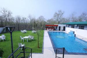 a swimming pool with tables and chairs next to a building at Corbett Caves in Rāmnagar
