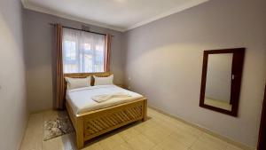 a small bedroom with a bed and a mirror at Dolphin AIR B&B in Arusha