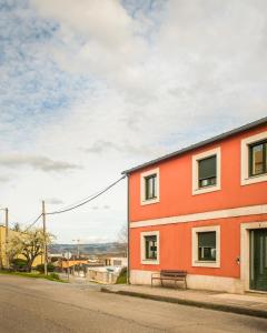 an orange building with a bench next to a street at Pensión Casa Rego Sarria in Sarria