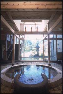 a large pool of water in a building with a fountain at Okada Ryokan Warakutei in Takayama