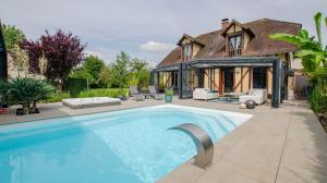 a swimming pool in front of a house at La Villa Séquoia in Les Bordes-Aumont