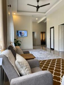 a living room with a couch and a tv at Homestay Lanai Kemboja Sungai Buloh in Shah Alam +2 photos