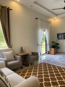a living room with a couch and chairs and a table at Homestay Lanai Kemboja Sungai Buloh in Shah Alam