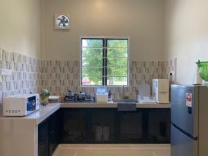 a kitchen with a sink and a refrigerator at Homestay Lanai Kemboja Sungai Buloh in Shah Alam