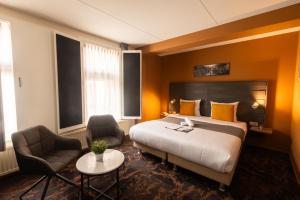 a hotel room with a bed and two chairs at Hotel The Happy Traveler in Groningen