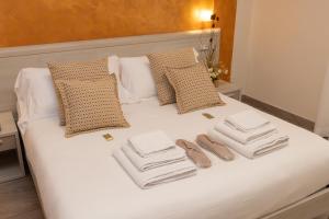 a white bed with three towels and two pairs of shoes at B&B Domus Vettii in Pompei