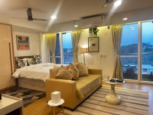 a bedroom with a bed and a couch and windows at Atelier Sol- ultra luxe aparthotel near airport in Pune +38 photos