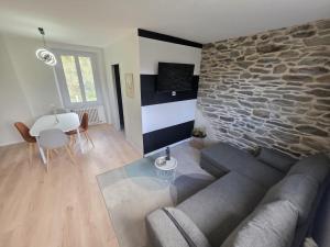 a living room with a couch and a stone wall at L'hyère in Carhaix-Plouguer